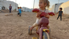 Despite the baking summer sun, IDP kids play on sand, sunk in dust